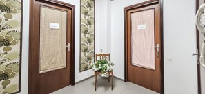 A hallway with two wooden doors labeled 'Il Vico 1' and 'Il Vico 2,' a small wooden chair with a floral arrangement, and a telephone on the right wall. - Il Vico 2 - Pozzallo (Pozzallo)