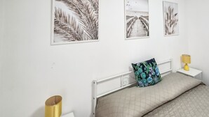 Ein Schlafzimmer mit einem Bett, einem Nachttisch, einer Lampe und drei gerahmten Bildern an der Wand.