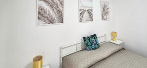 A bedroom with a bed, a nightstand, a lamp, and three framed pictures on the wall. - Il Vico 2 - Pozzallo (Pozzallo)