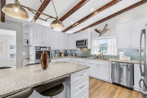 A kitchen with white cabinets, a granite countertop, a stainless steel dishwasher, and a microwave. - HOLIDAY SHORES BEACH COTTAGE! WATERFRONT! DOCK! WALK TO BEACH! PET FRIENDLY!!! (Fort Myers Beach)
