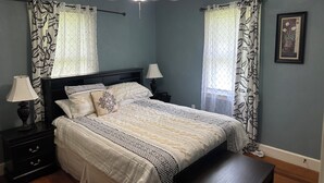A bedroom with a bed, two bedside tables, a ceiling fan, and a window with patterned curtains. - Spacious, Cozy and Quiet 3 Bedrooms and 2 Bathrooms Located 12 min to downtown (Savannah)