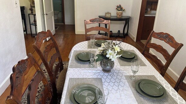 A dining area with a table set for four, chairs, a vase with flowers, and a painting on the wall. - Spacious, Cozy and Quiet 3 Bedrooms and 2 Bathrooms Located 12 min to downtown (Savannah)