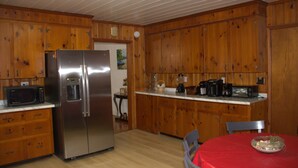 A kitchen with wooden cabinets, a stainless steel refrigerator, a microwave, and a dining table with a red tablecloth. - Spacious, Cozy and Quiet 3 Bedrooms and 2 Bathrooms Located 12 min to downtown (Savannah)
