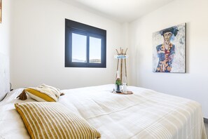 A bedroom with a bed, a window, a painting, and a small table with a bottle and glass. - Orizon, Algarrobo Costa (Algarrobo Costa)