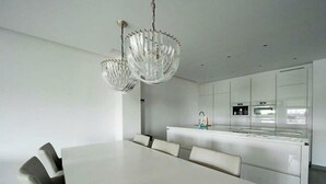 A modern kitchen with white cabinetry, a central island, and a dining area with a white table and chairs. - Zuiderzee Luxe 6 (Uitdam)