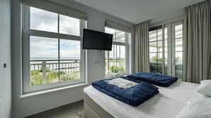 A hotel room with a bed, a TV, and large windows with a view. - Zuiderzee Luxe 6 (Uitdam)