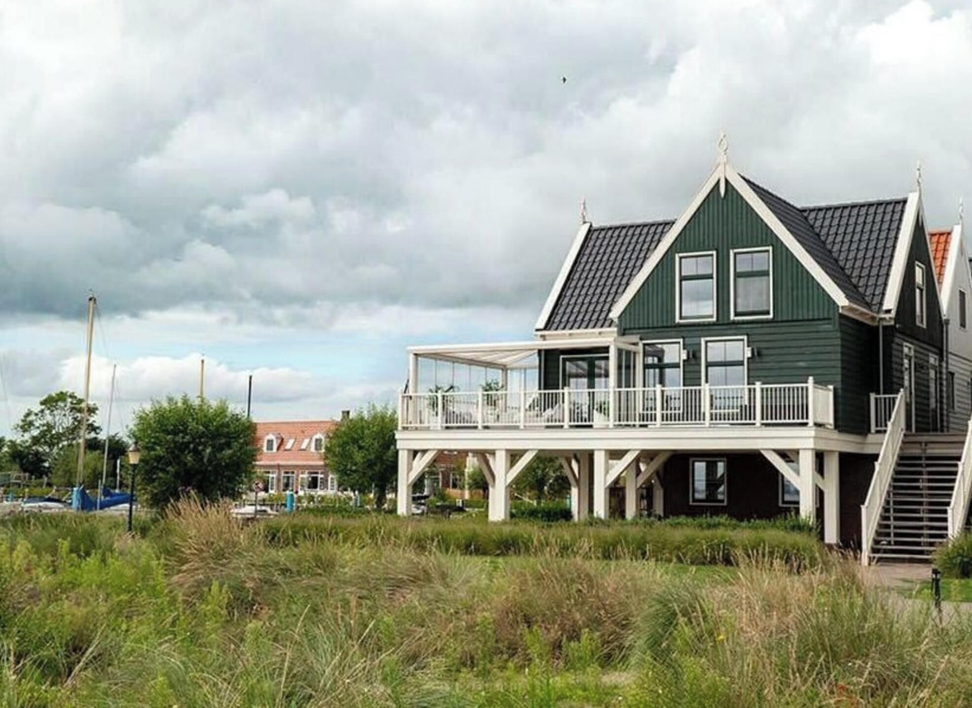 A green house with a balcony and a staircase leading to the entrance.