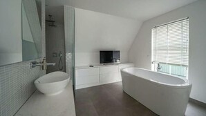 A modern bathroom with a freestanding bathtub, a large mirror, a sink, and a shower area. - Zuiderzee Luxe 6 (Uitdam)