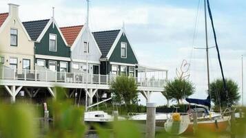A waterfront property with a dock, a sailboat, and a row of houses with a balcony.