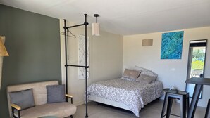 Un dormitorio con cama, sofá, lámpara colgante y un gato.