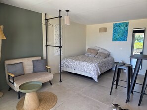 Ein Schlafzimmer mit Bett, Sofa, Pendelleuchte und einer Katze.