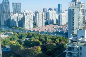 Um edifício residencial alto com várias varandas, em um ambiente urbano denso e uma rodovia em primeiro plano.