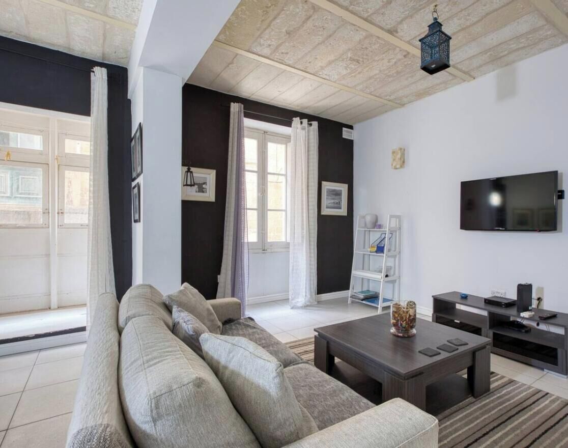 Una sala de estar con un sofá, una mesa de centro, un televisor y una estantería.