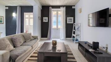 Una sala de estar con un sofá, una mesa de centro, un televisor y una estantería.