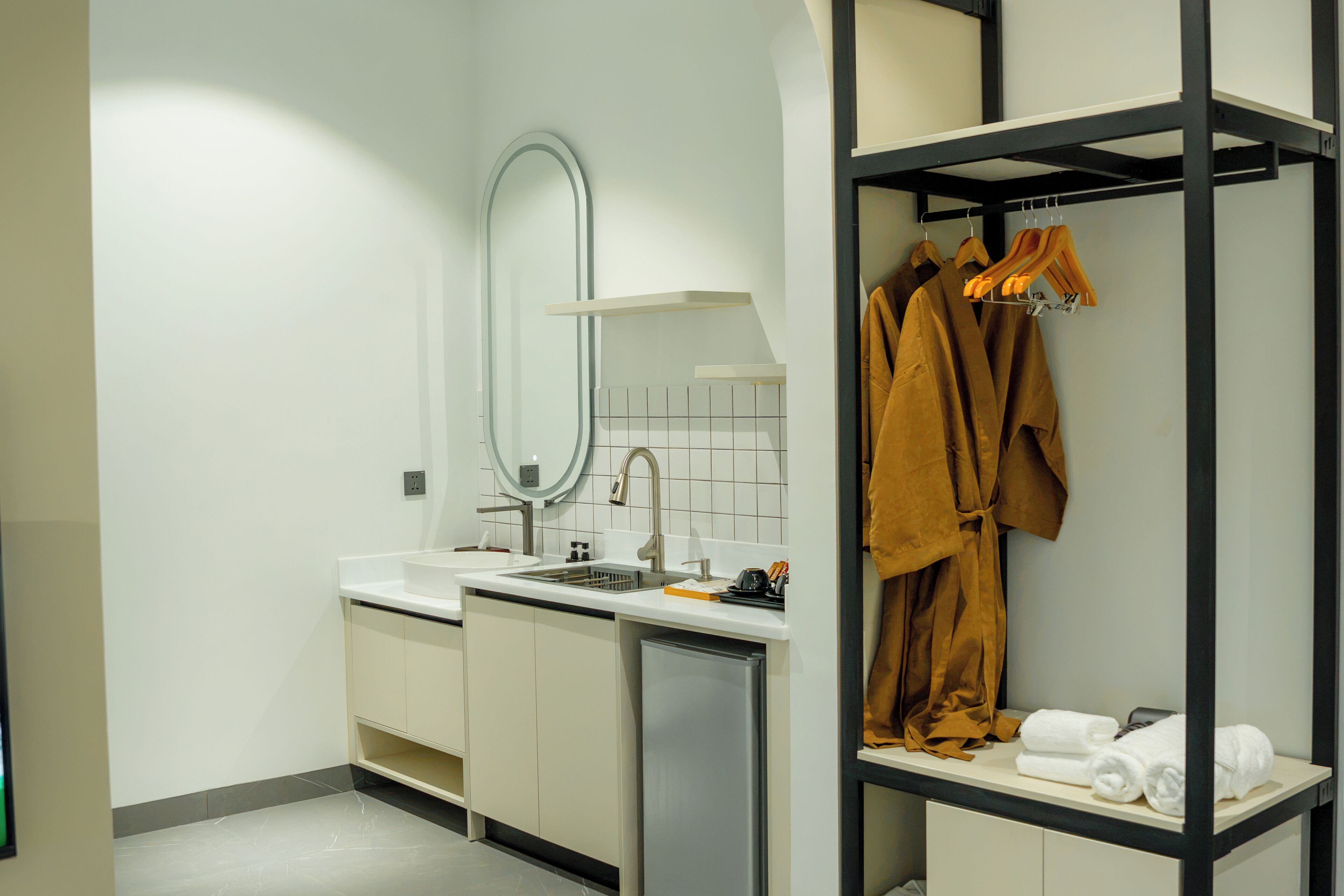 A modern bathroom with a sink, mirror, and towel rack.