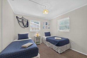 A bedroom with two beds, a nightstand, a wall-mounted light fixture, and a window with blinds. - 3BR Private Pool Home Near Indian Rocks Beach & Clearwater Pets + Fenced Yard (Largo)