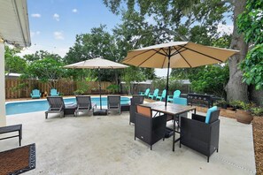 Ein Garten mit Pool, Gartenmöbeln und Grill.