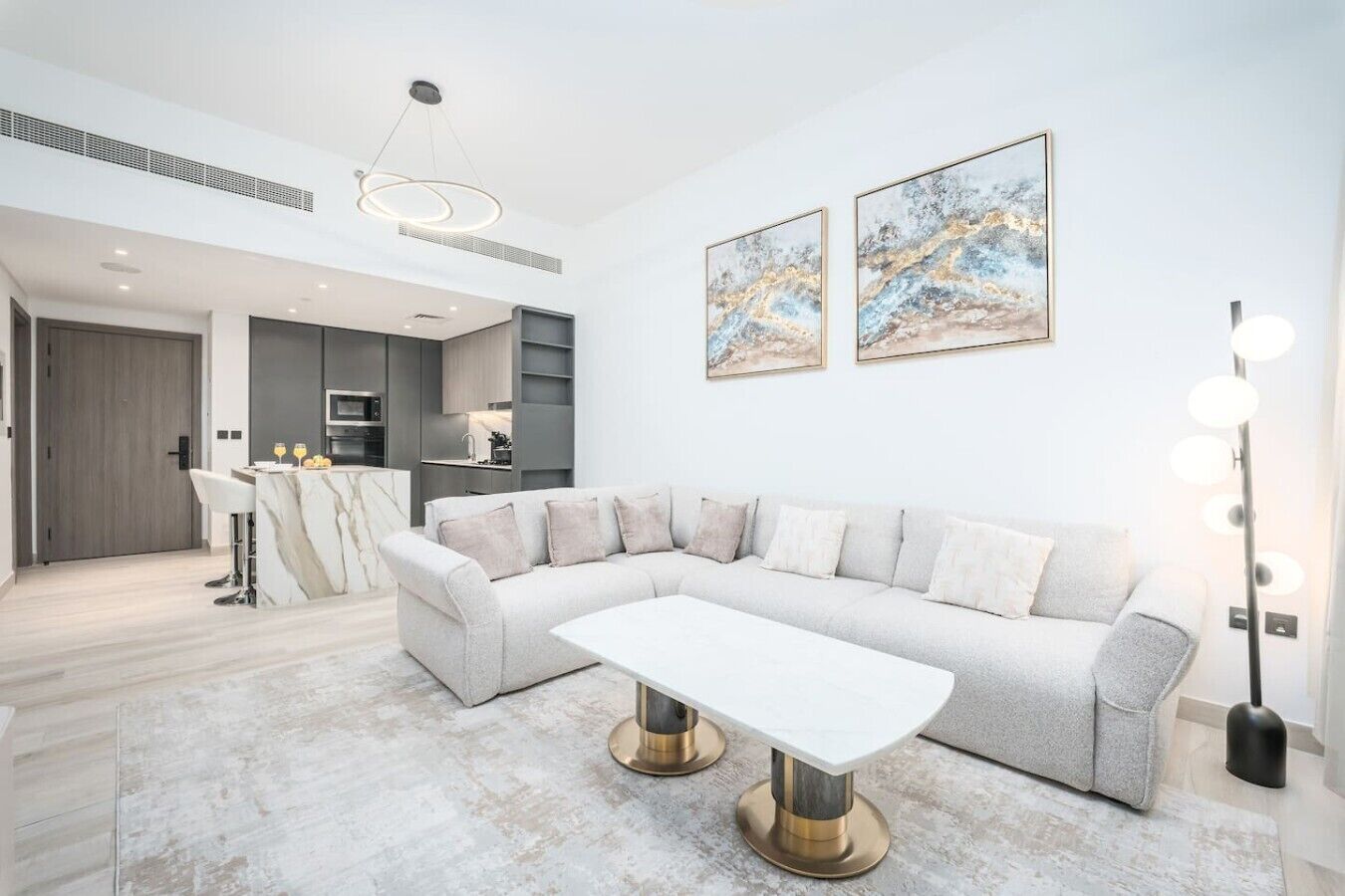 A modern living room with a sectional sofa, a dining table, and a kitchen in the background.