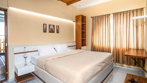 Een moderne hotelkamer met een groot bed, nachtkastjes, een houten plankunit, een kleine tafel en een kamerplant.