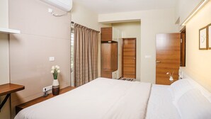 Een hotelkamer met een groot bed, een bureau, een kledingkast en een airconditioning.