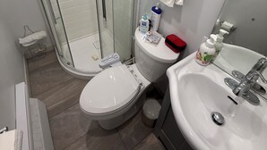 Een badkamer met een douchecabine van glas, een toilet, een wastafel en toiletartikelen.