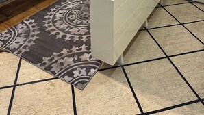 Een kamer met een bed, een klein tafeltje, een kamerkleed met patroon en een witte bank.