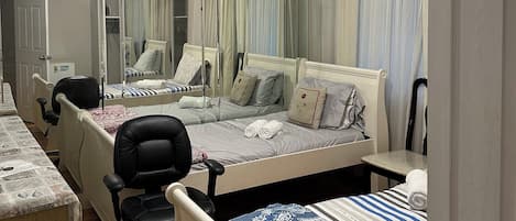 A hotel room with a large bed, a desk, a chair, a mirror, and a ceiling light fixture.