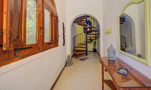 A wooden door with glass panels, a staircase with a metal railing, a small Buddha statue, and a mirror on the wall. - Gozo Couple Bungalow No 2 · Pool, Cabana, BBQ Deck (Gozo)