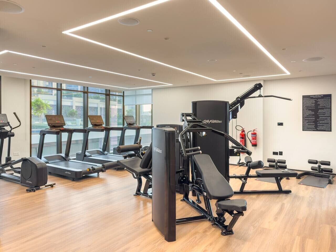 A modern gym with treadmills, weight machines, and a large mirror.