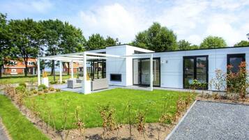 A modern building with a covered outdoor seating area, a gravel path, and a well-maintained lawn.
