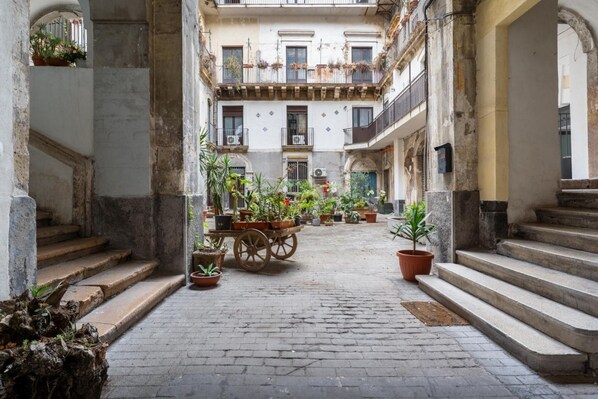 A courtyard with a central garden, stone steps, and a building with balconies.