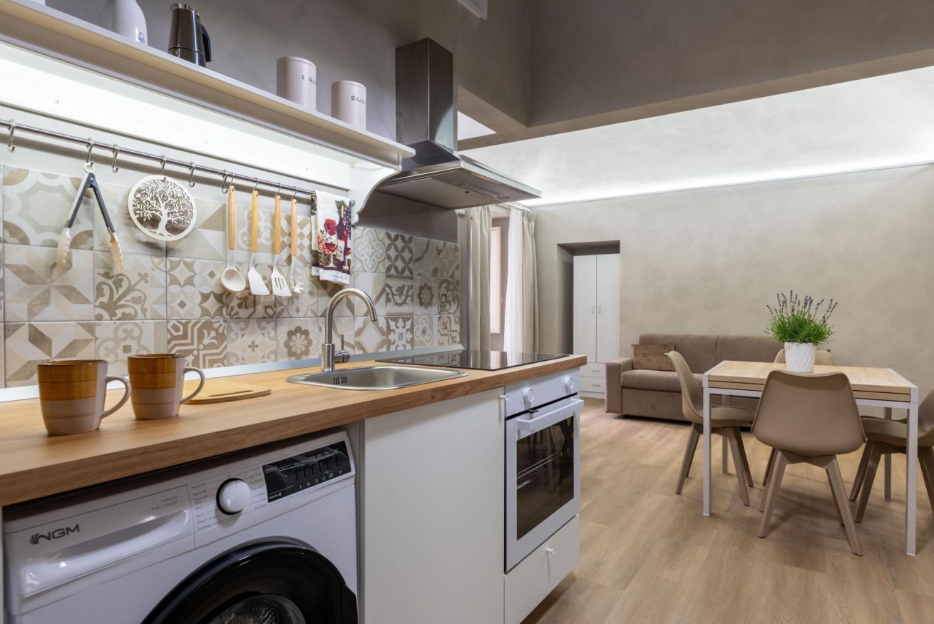 Une cuisine compacte équipée d’un lave-linge, d’une cuisinière, d’un évier et d’un coin repas avec des chaises et une table.