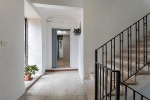 Ein Flur mit Treppe, einer Topfpflanze und einer Tür zu einem anderen Raum.