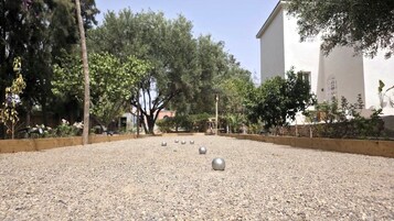 Un patio con superficie de grava, árboles y un edificio al fondo.