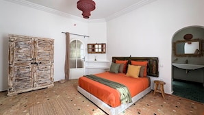 Un dormitorio con cama, armario, espejo y lámpara colgante.