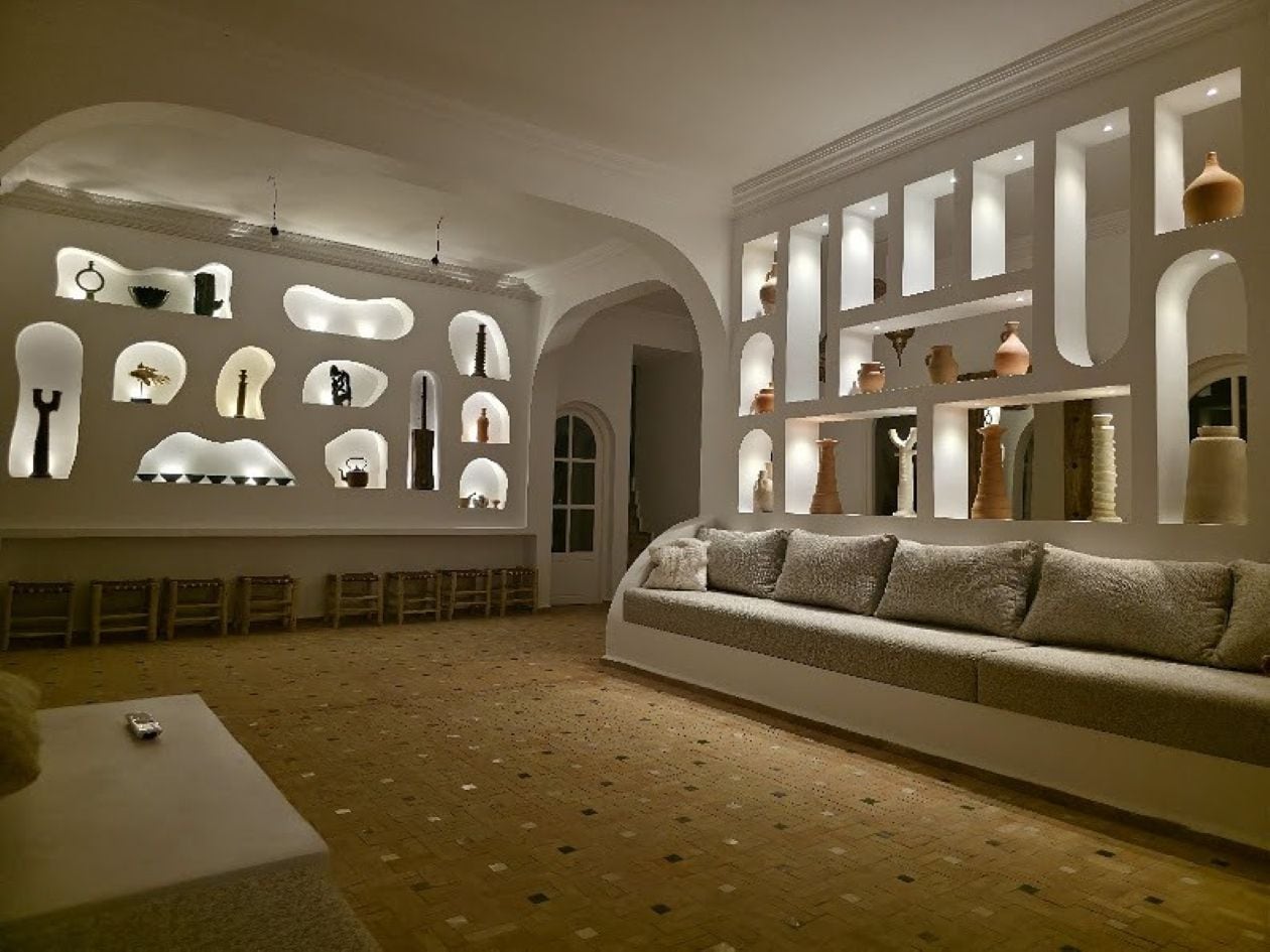 A modern interior with a sofa, a dining table, and a wall displaying various objects.