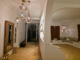 Una habitación con pared blanca curva, un sofá, un espejo y lámparas colgantes.