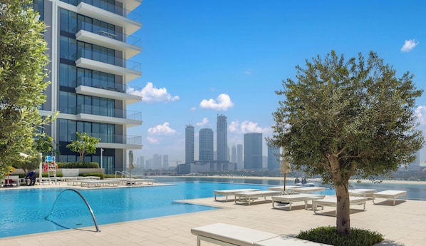 Ein modernes Gebäude mit Pool, Liegestühlen und Blick auf die Stadtlandschaft.