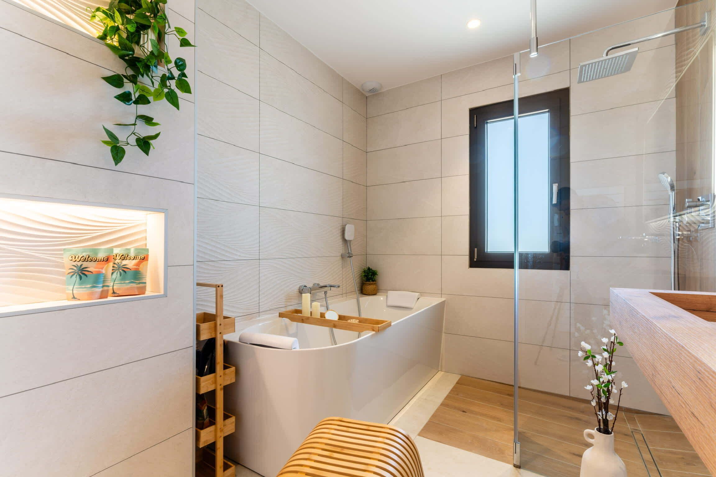 Een moderne badkamer met een vrijstaand bad, een douchecabine van glas en een houten bankje.