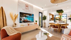 A modern living room with a TV, sofa, dining table, and a sign reading 'DOLCE VILLA'. - La Dolce Villa | Villa 5 étoiles, piscine chauffée, 700 m plage (Sérignan)