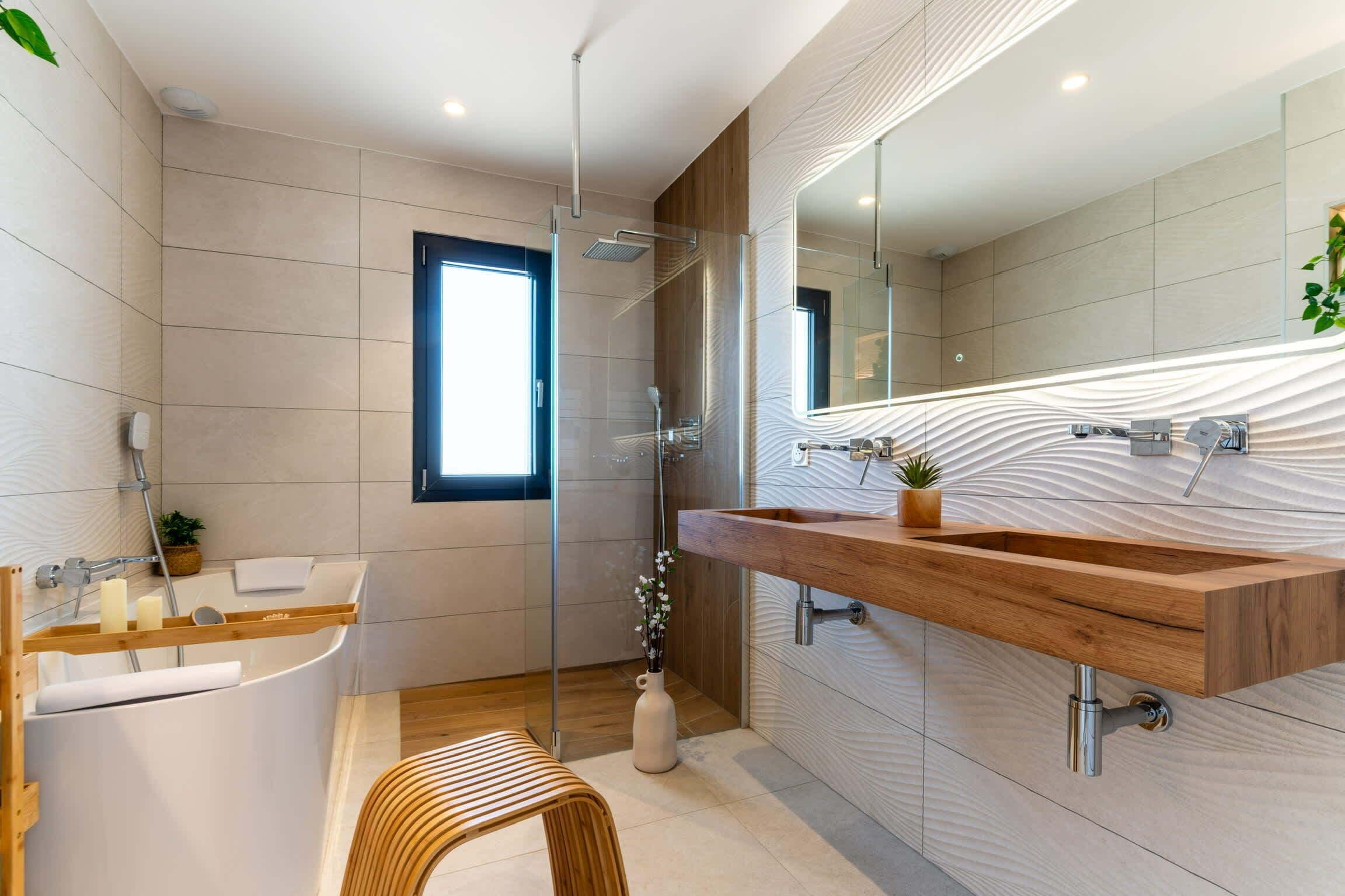 Un baño moderno con tocador de madera, cabina de ducha de vidrio y un espejo grande.