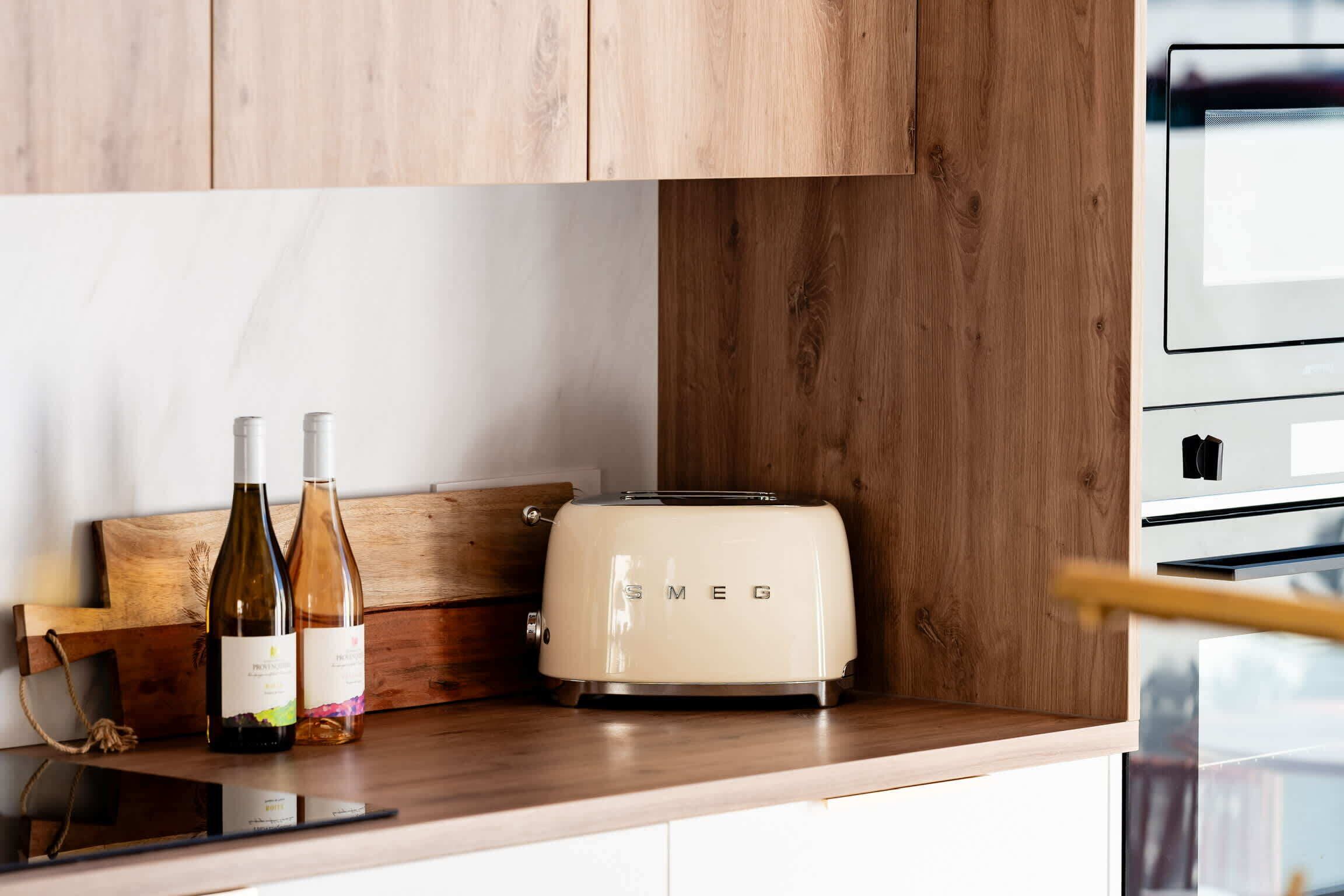 A kitchen with a wooden countertop, a vintage Smeg toaster, and two wine bottles.
