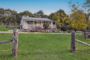 A small, single-story building with a porch, surrounded by a fenced yard and trees. - Glen Eden Estate - Entire Estate (Broke)