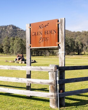 Ein Holzschild mit der Aufschrift 'Glen Eden Estate', an einem Metallpfosten befestigt.