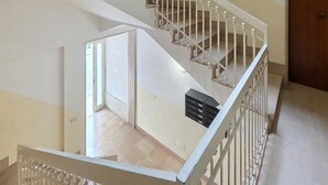 Ein mehrgeschossiges Interieur mit Treppe, einer Tür und einem Lichtschalter an der Wand.