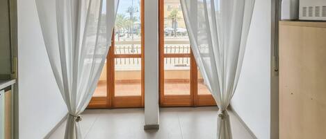 Una habitación con vistas, visible a través de una puerta de madera, una pared blanca y un armario de madera.