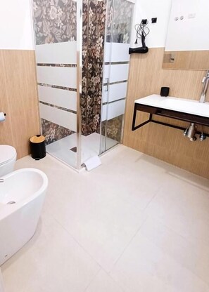 Ein Badezimmer mit Toilette, Bidet und Duschbereich.