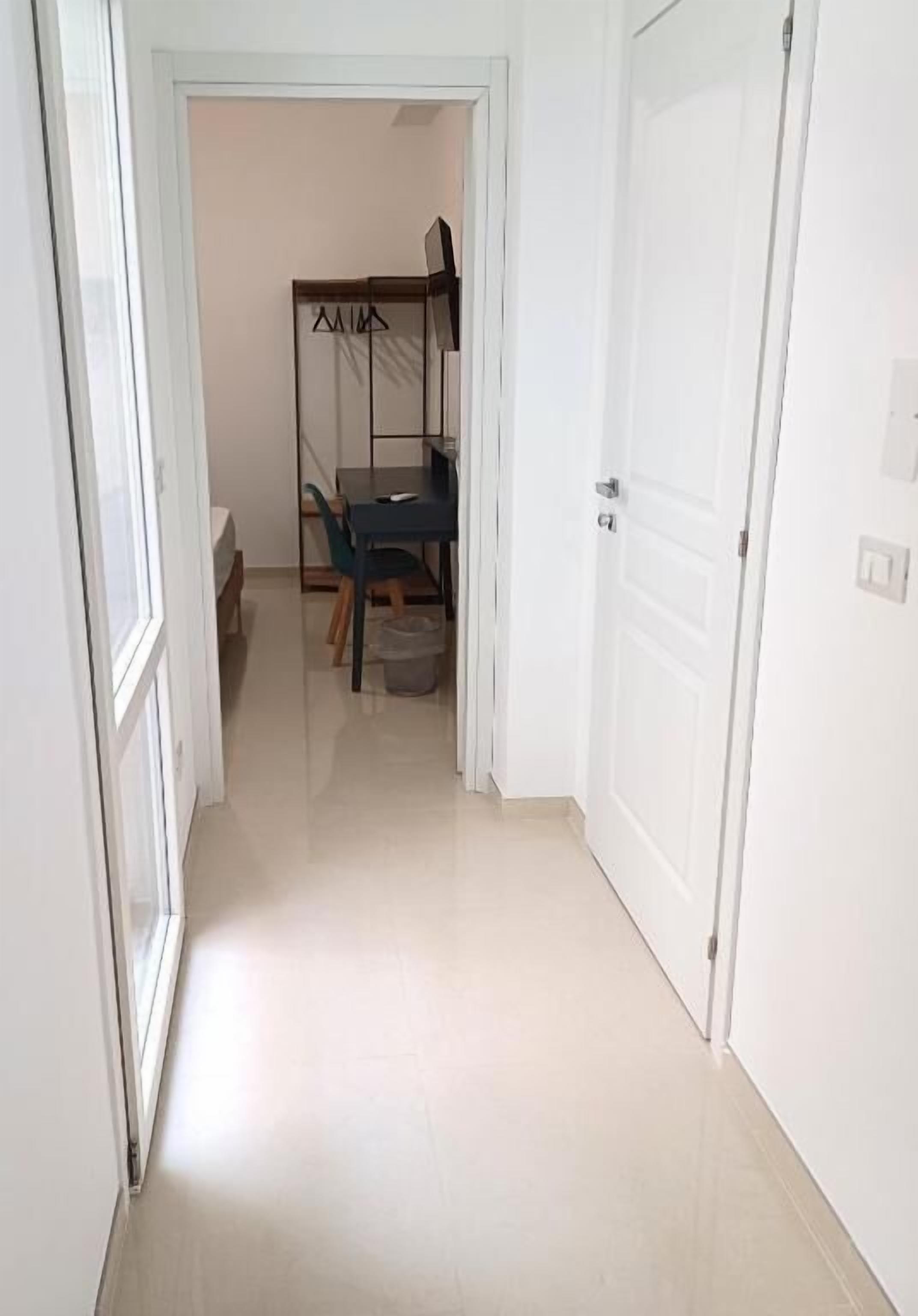 A narrow hallway with a bunk bed and a desk in the background.