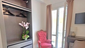 A hotel room with a bed, a chair, a desk, a TV, and a wardrobe. - Vegan B&B (Syracuse)