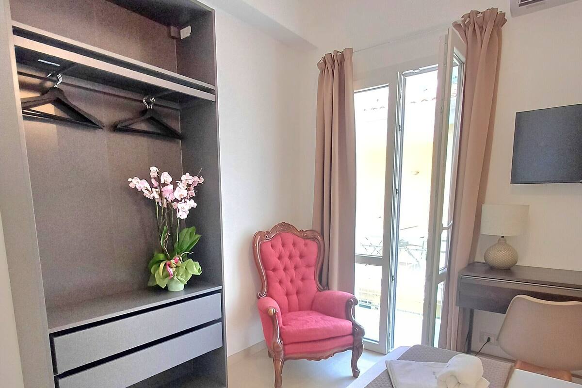A hotel room with a bed, a chair, a desk, a TV, and a wardrobe.